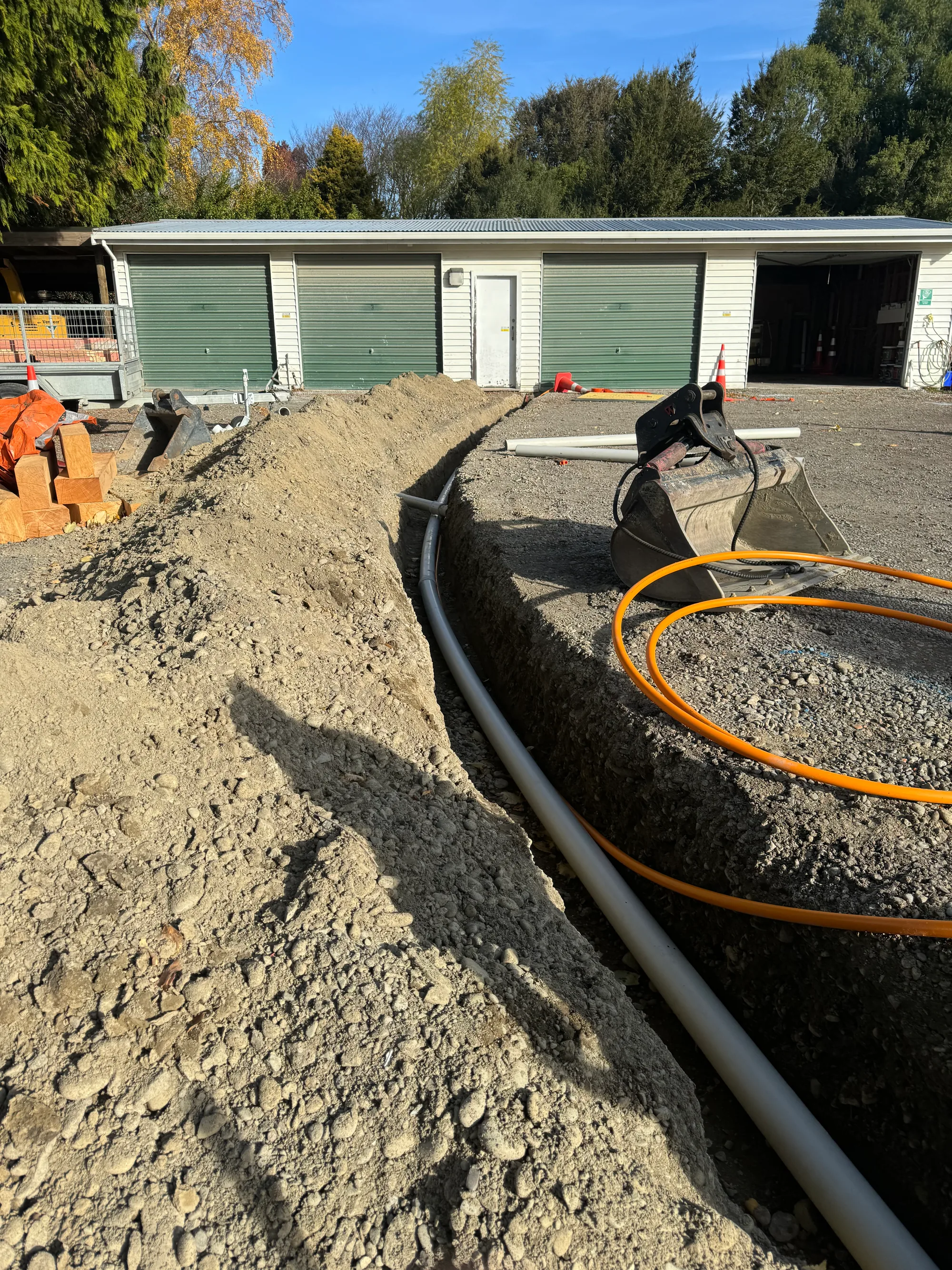 Excavator digging services trench on Canterbury contractor site