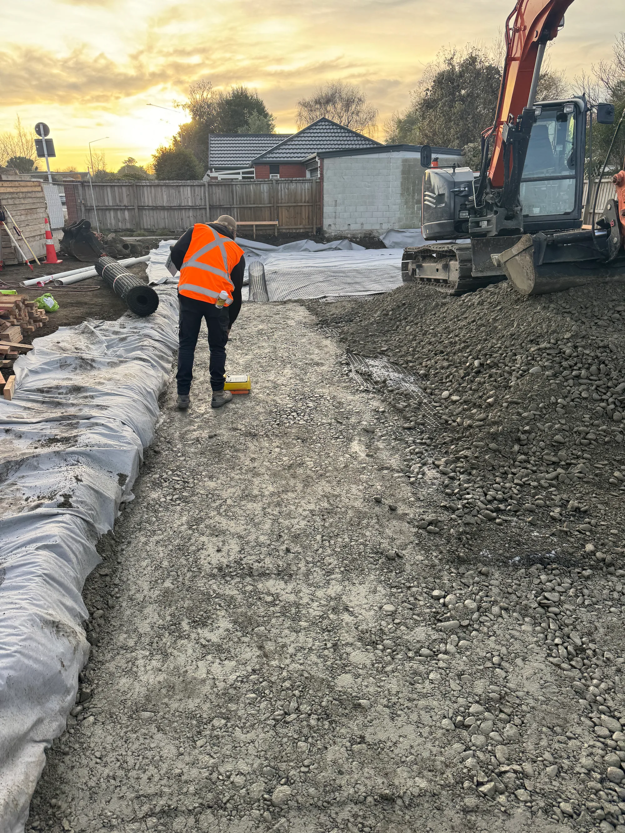 Excavator operator and machine working together on Canterbury site at golden hour